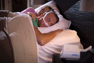 Photo d'un couple endormi avec la PPC DreamStation Expert et le masque DreamWear