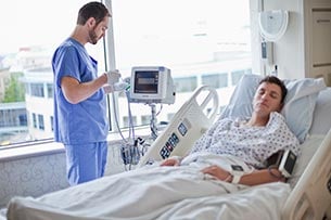 un homme debout à côté d'un patient dans un lit d'hôpital