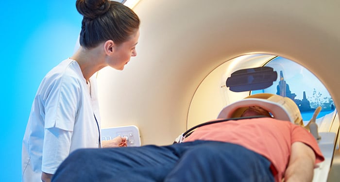 une femme regardant un homme allongé dans un scanner