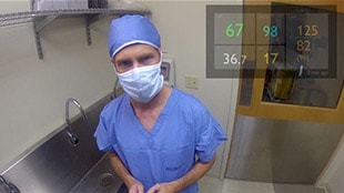 Un médecin au bloc opératoire avec les paramètres vitaux affichés dans le coin supérieur droit de son champ de vision.