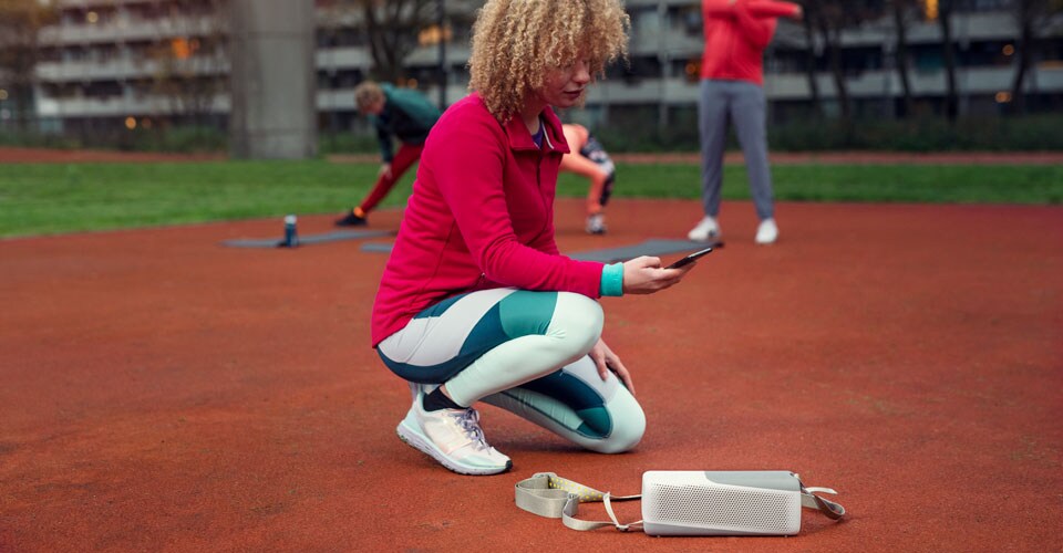 Femme se connectant à son enceinte Bluetooth Philips à l'extérieur