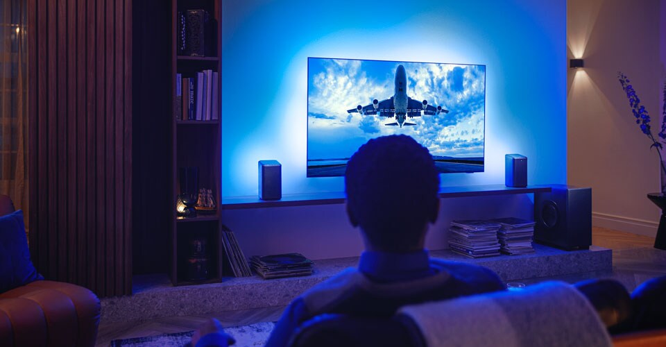 Homme profitant de son téléviseur Philips Ambilight connecté aux enceintes sans fil Philips FS1