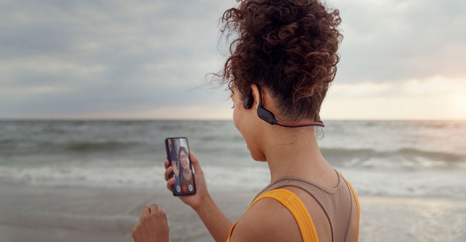 Athlète passant un appel sur la plage à l'aide d'un casque à conduction osseuse