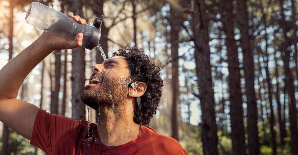 Un athlète verse de l'eau sur des écouteurs étanches à oreille ouverte