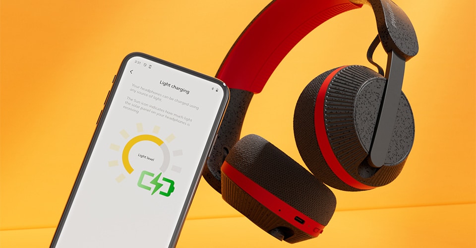 Casque Philips A6219 à côté d'un smartphone affichant l'écran de chargement lumineux, sur un fond orange vif