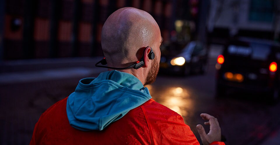 Homme portant des écouteurs à oreille ouverte dans une rue bondée