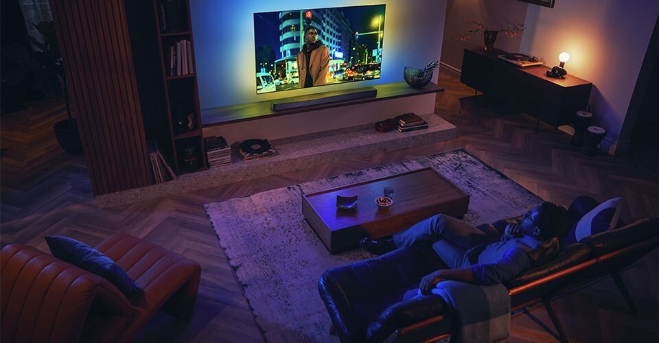 Homme profitant de son téléviseur Philips Ambilight avec barre de son