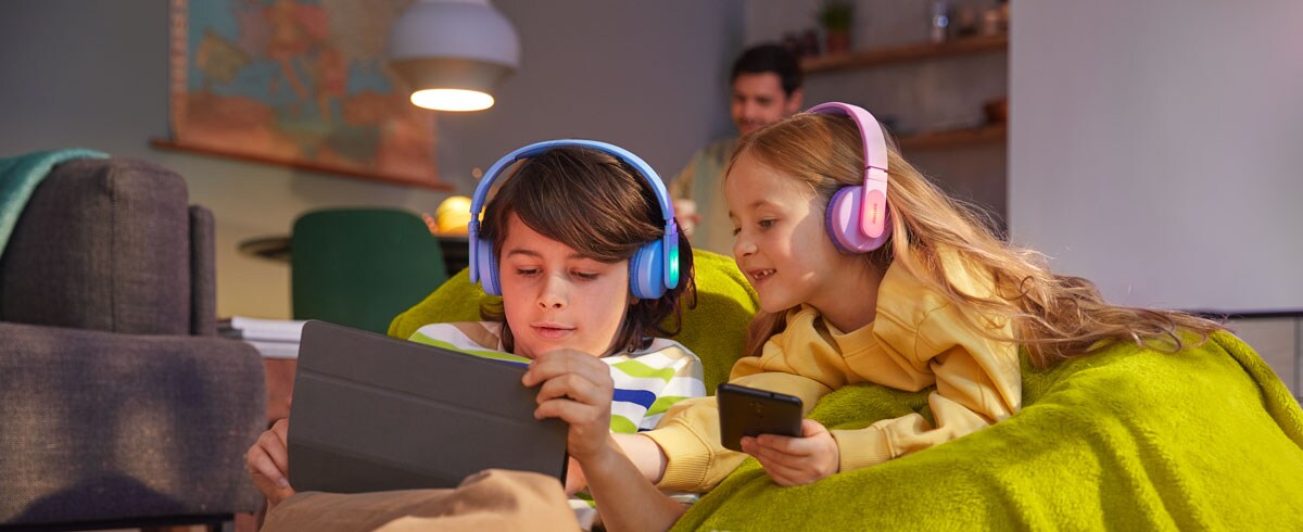 Un garçon et une fille utilisent leurs appareils tout en utilisant des écouteurs durables pour enfants