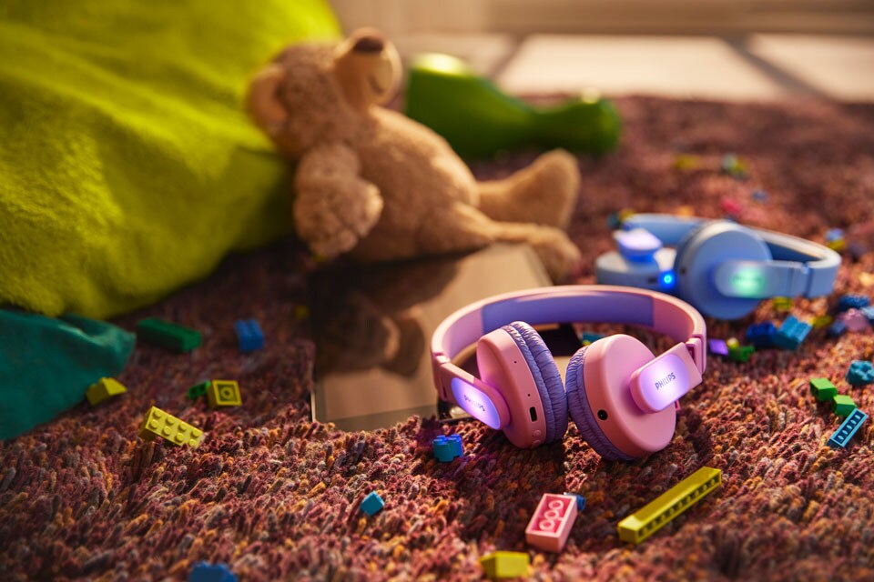 Un casque bleu et un casque rose sur le sol avec des jouets
