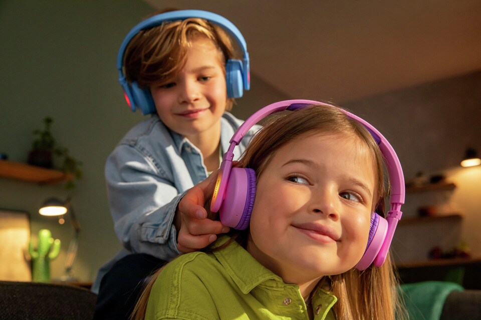 Deux frères et sœurs jouant avec des écouteurs intra-auriculaires pour enfants
