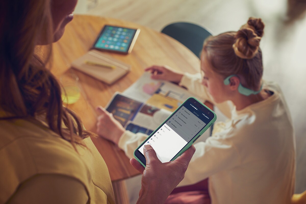 Un parent utilise l'application Philips Headphones pour contrôler le volume des écouteurs pour enfants.