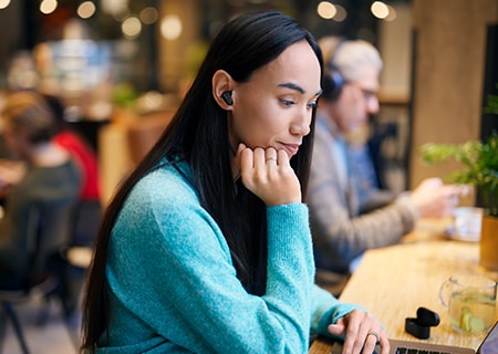 Femme étudiant dans un café utilisant un casque sans fil à réduction de bruit Philips T3508