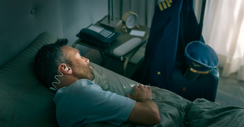 Un homme dort confortablement sur le côté grâce à un casque de sommeil Philips.