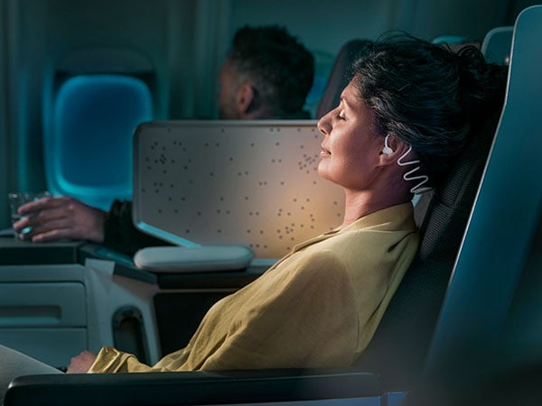 Femme dormant dans l'avion avec un casque spécial sommeil Philips TAN7808