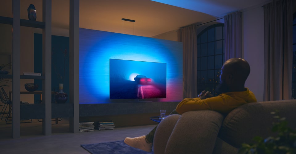 Un couple regarde un film sur un téléviseur Ambilight