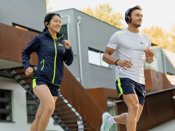 Deux athlètes participant à la course courent ensemble en portant un casque et des écouteurs Philips.