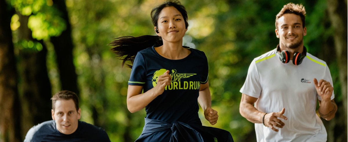 Trois participant-es à la Wings for Life World Run portant des casques sport Philips courent joyeusement.