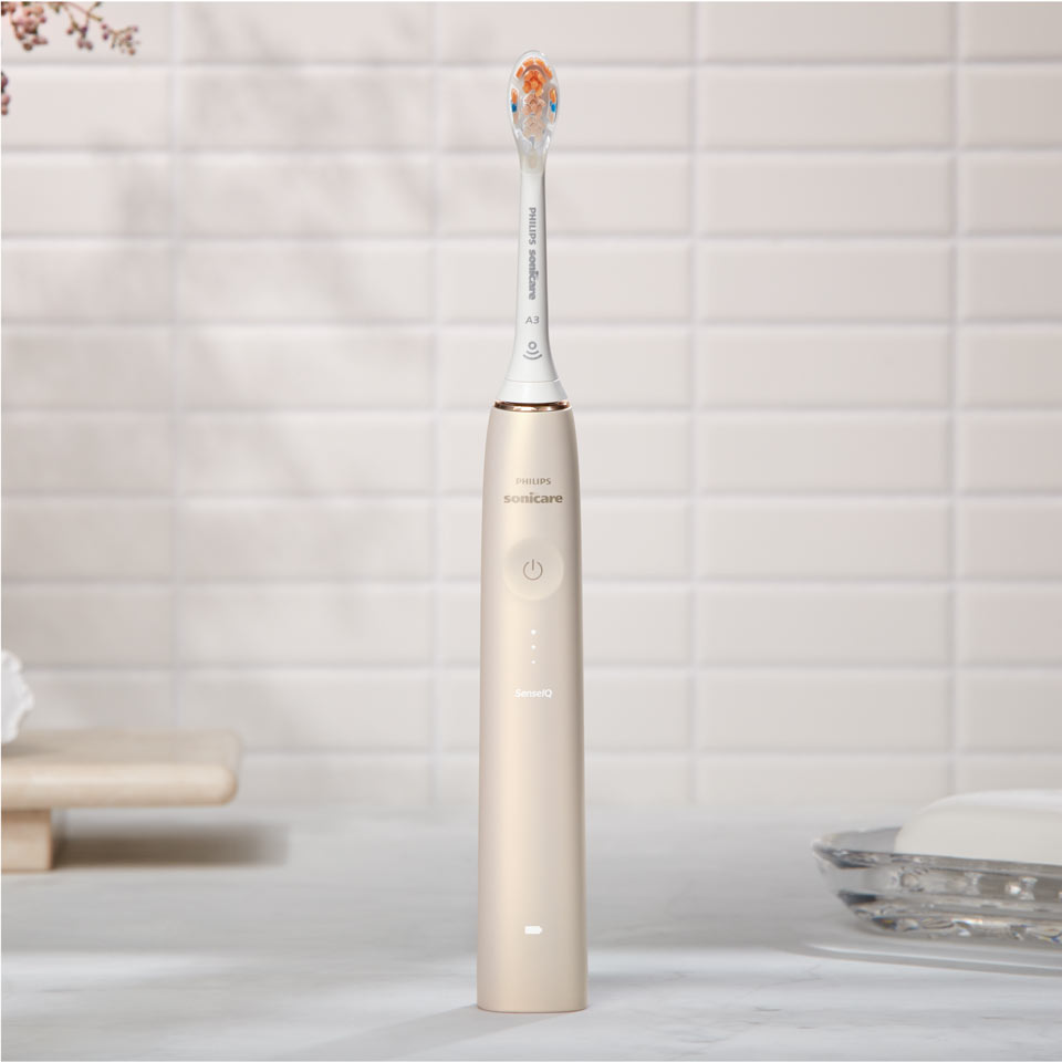 Brosse à dents électrique Philips Sonicare Prestige 9900 avec la tête de brosse tout-en-un posées sur un plan de travail