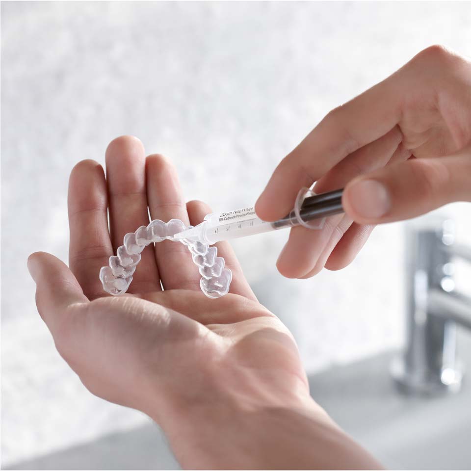 Patient appliquant du gel éclaircissant sur une gouttière sur mesure