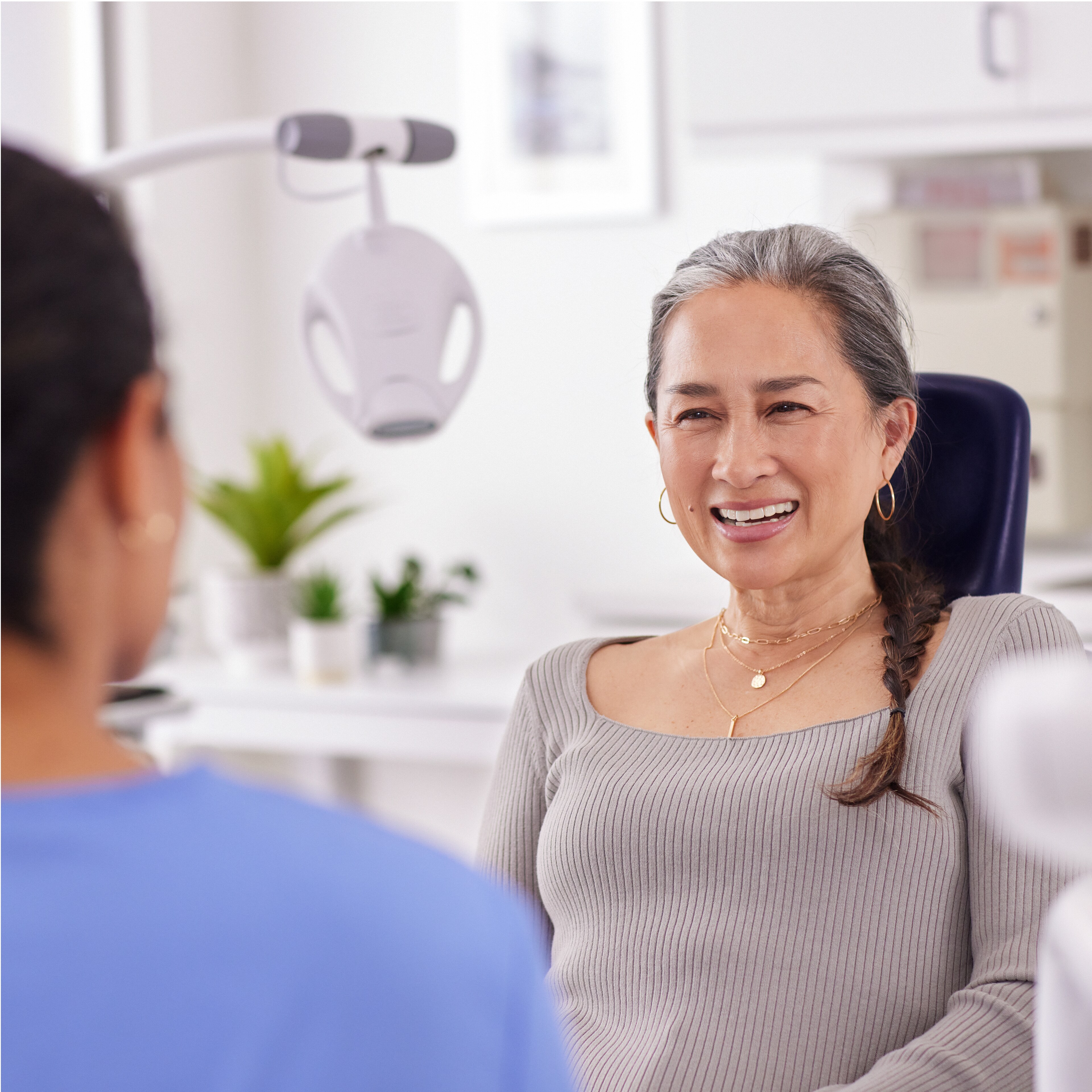 Une patiente discutant avec une professionnelle de la santé bucco-dentaire et une lampe Philips Zoom! WhiteSpeed en arrière-plan