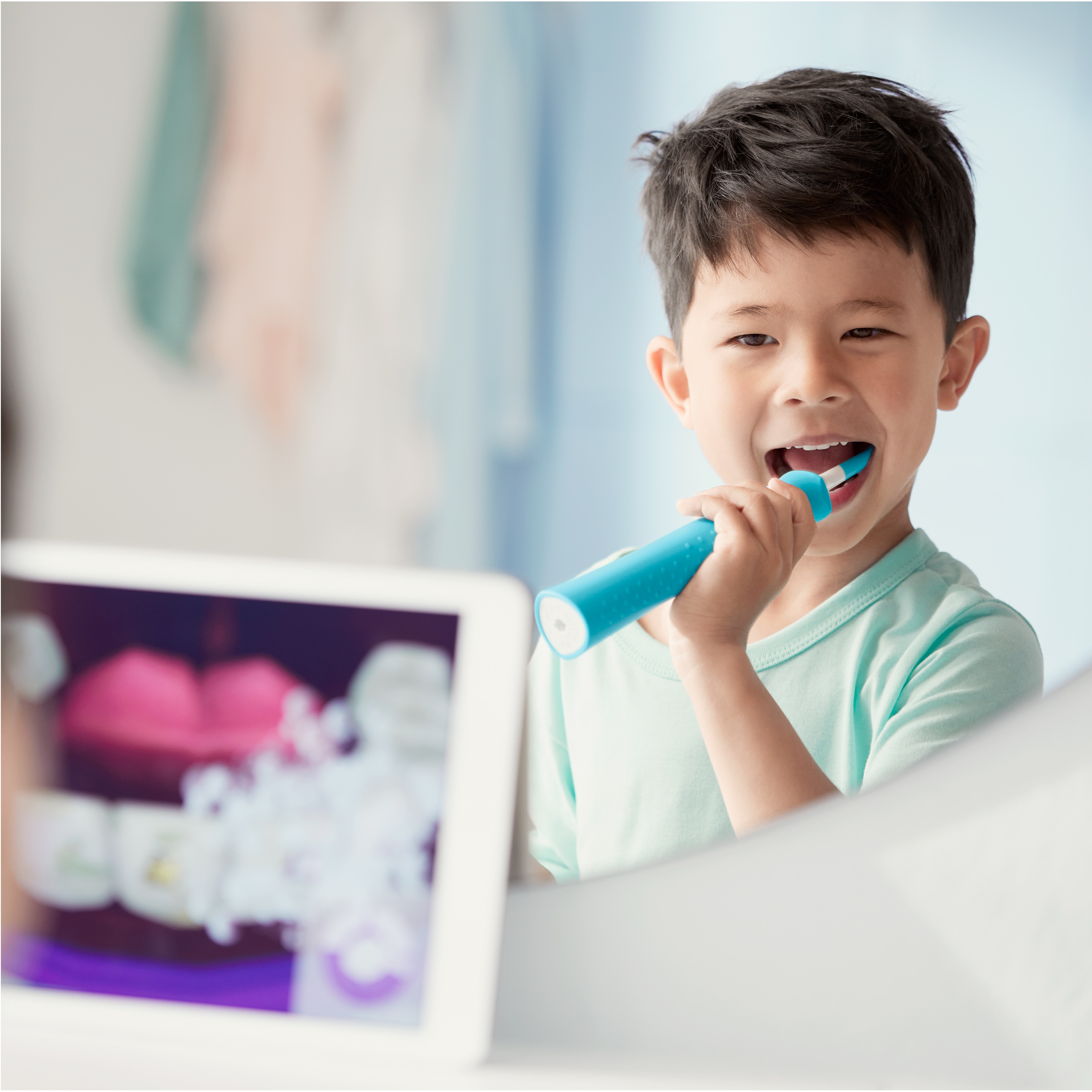 Garçon utilisant une brosse à dents électrique Sonicare for Kids tout en regardant l'application Sonicare for Kids