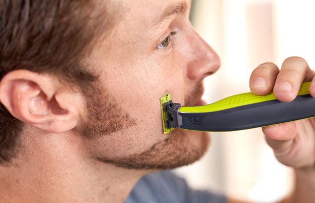 Visage d’un homme qui s’est rasé une ligne sur le côté droit de sa barbe avec un rasoir.