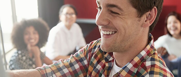 Gros plan sur le visage dun homme souriant, avec quatre personnes floues en arrière-plan