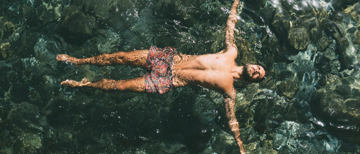 Un homme flotte à la surface de leau, les bras et les jambes tendus et les yeux fermés.