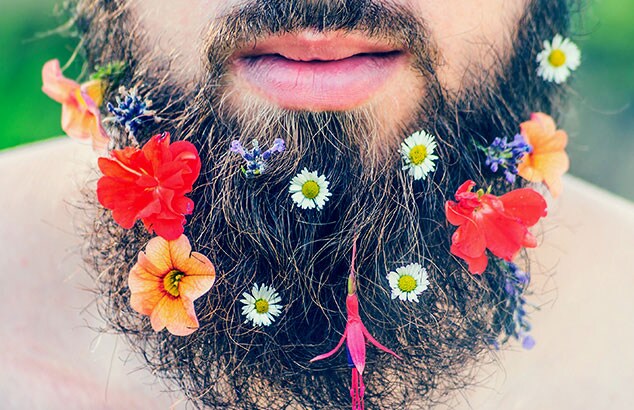 Gros plan sur la barbe d'un homme à laquelle ont été ajoutées de nombreuses fleurs différentes et colorées.