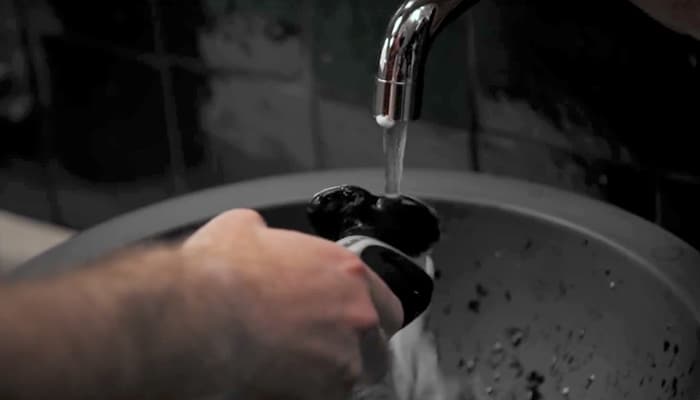 Une personne lave un rasoir Philips à l’eau courante après s’être rasé.