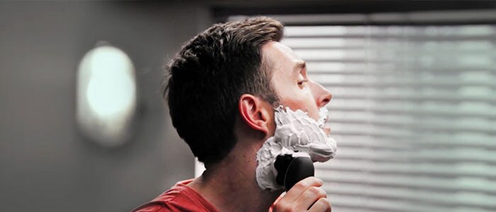 Profil latéral d’un homme se rasant avec un rasoir électrique.