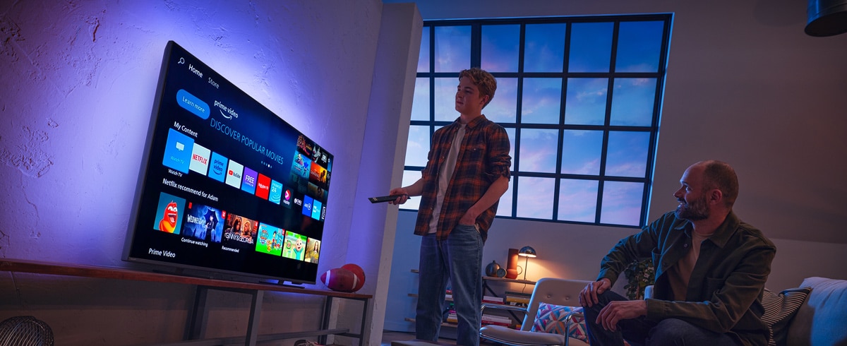 Un homme choisissant une application sur le téléviseur Philips Smart TV